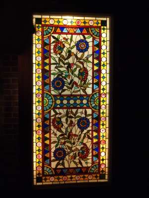 [Light shining through a stained glass window with flowers in the display.]